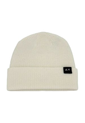 Beanie lavorato a maglia in beige chiaro, caratterizzato da un risvolto e un piccolo etichetta nera con un logo bianco sul lato. Texture morbida e design semplice.