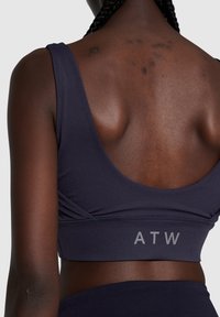 Marine sportbeha met een ronde rug, accentueert door een lichter band met de tekst "ATW." Gladde textuur met minimale naden.