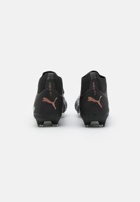 Scarpe da calcio nere con superficie texture, caratterizzate da un design aderente, accenti metallici e un logo sul tallone.