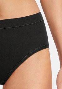Schwarze Baumwollunterwäsche mit hohem Bund, glatter Textur und minimalen Nähten, die ein enganliegendes Design zeigt.