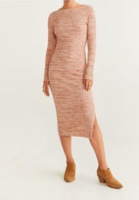 Abito midi in maglia a coste rosa pallido con maniche lunghe e spacco laterale, abbinato a stivaletti beige con tacco a blocco.