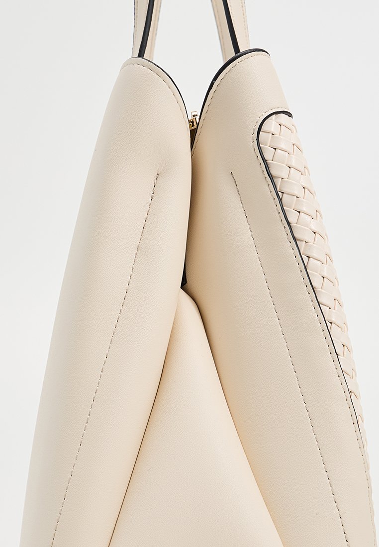 Crème leren handtas met een geweven zijpaneel, zwarte afwerking en gouden ritssluiter, bekeken vanuit een bovenaanzicht dat de details benadrukt.
