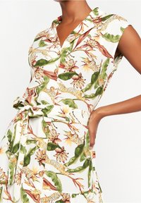 Kwiatowa sukienka z guzikami z zielonymi, żółtymi i czerwonymi nadrukami botanicznymi na białym tle; materiał jest lekki i ma paski w talii.