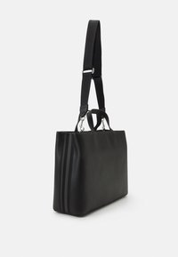 Sac en cuir noir au design structuré, doté d'une bandoulière amovible et de deux poignées, agrémenté d'un détail de zip texturé sur le côté.