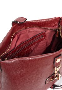 Bolso de mano de cuero rojo con una superficie texturizada, que cuenta con un interior espacioso, cremalleras doradas y un bolsillo para la organización.