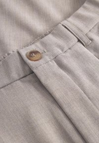 Grau melierte Stoffhose mit sichtbarer Textur, ausgestattet mit einem Knopfverschluss aus hellbraunem Material und einem gefalteten Vorderdesign.