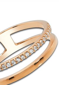 Bague en or rose avec des anneaux entrelacés. Un anneau est lisse, tandis que l'autre est orné de petits pierres précieuses scintillantes sur toute sa longueur.