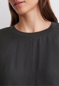 Maglione grigio scuro a girocollo con una texture liscia, caratterizzato da un design semplice e da dettagli di cucitura discreti lungo il collo.