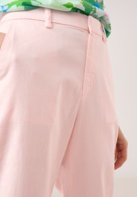 Hellrosa, weite Hosen aus weichem Stoff mit glatter Textur. Mit klassischem Bund und Seitentaschen.
