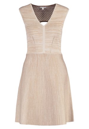 Beige tekstuuriakankainen hihaton mekko V-pääntiellä, yhdistettynä mustaan nahkalaukkuun, jossa on kultainen lukko. Mustat liukuvarrelliset kengät korostuksilla.