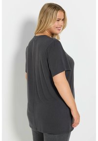 Mörkgrå kortärmad t-shirt med en avslappnad passform. Har en rundad halsringning och subtil dekorativ detaljering nära axelsömmen.