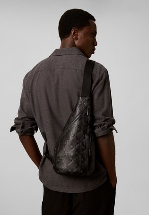 Calvin Klein, CALVIN KLEIN DEBOSSED ALLOVER EMBLEM LOGO SLING BAG - Rucksack - black