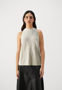 Light gray sleeveless top with a textured surface, high neckline, and relaxed fit, paired with a black leather skirt featuring visible seams.
