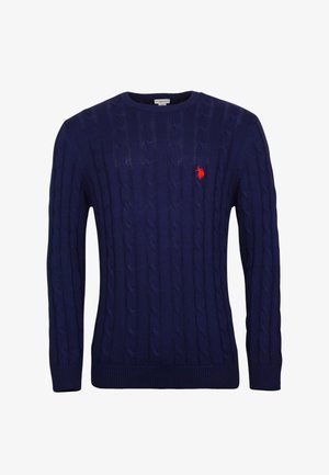 Marinblå kabelstickad tröja med rund halsringning, ribbade ärmslut och nederkant. Har en liten röd logotyp på bröstet. Tillverkad av tjockt stickat material.