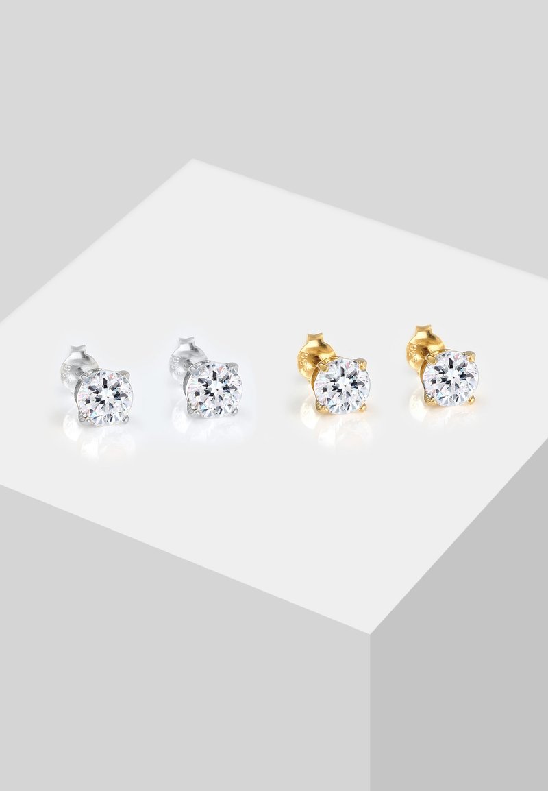 Pendientes de studs de plata y oro con cristales claros redondos; montura de bisel con motivos florales; acabado pulido; se muestran dos pares.
