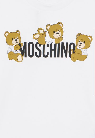Camiseta blanca con tres osos de dibujos animados y el texto "Moschino" en letras negras en negrita. Los osos son marrones con acentos claros.