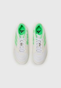 Baskets de sport blanches avec des accents verts, des panneaux en maille et un design à trois bandes. Elles sont dotées de lacets blancs et d'un col rembourré pour plus de confort.