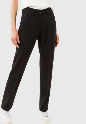 Pantalons noirs ajustés avec une coupe slim, dotés d'une fermeture à double bouton et de passants de ceinture. Texture lisse, design minimaliste, associés à des baskets blanches.