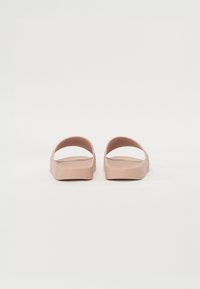 Růžové gumové sandály s otevřenou patou a dvěma širokými pásky na vrchu. Hladký povrch, minimalistický design, plochá podešev.