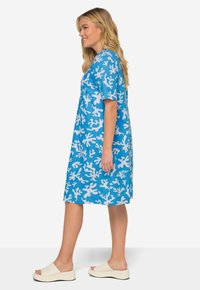 Vestido azul con patrón de coral blanco, de mangas cortas, diseño a la altura de la rodilla; combinado con zapatos blancos tipo slip-on, de textura suave.