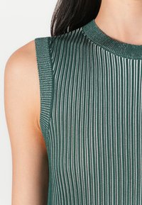 Sleeveless ribbed top in dark green with silver stripes. Features a round neckline and textured fabric. Smooth finish with slight sheen.