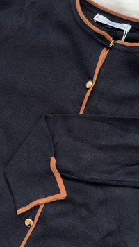 Granatowy kardigan z pomarańczowymi lamówkami, z okrągłym dekoltem, zapinany na guziki, o prążkowanej fakturze i zdobiony złotymi guzikami.