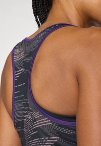 Schwarzes Sporttanktop mit lila Akzenten, das ein geometrisches Muster und ein Racerback-Design aufweist; der Stoff wirkt glatt und dehnbar.