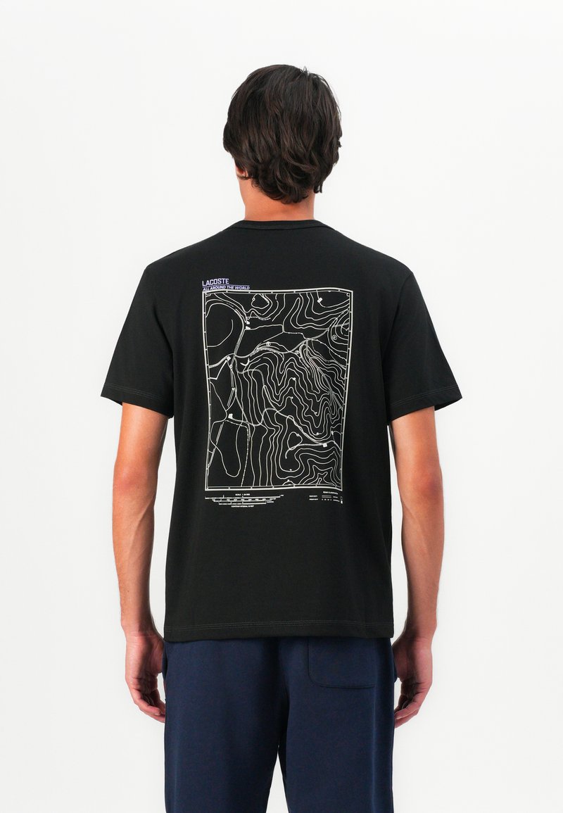 T-shirt noir en coton avec un graphique de carte en contour blanche au dos, avec des accents de texte en violet près de l'encolure. Coupe standard.