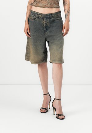 Denimshorts i en falmet blåfarge med løs passform og rå kant. Stilt med svarte stroppehyller og en gjennomsiktig brun topp.