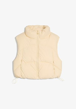 Kremno obarvan brezrokavnik iz odejnega materiala s visokim ovratnikom, sprednjim zadrgo in nastavljivimi vrvicami na robu.