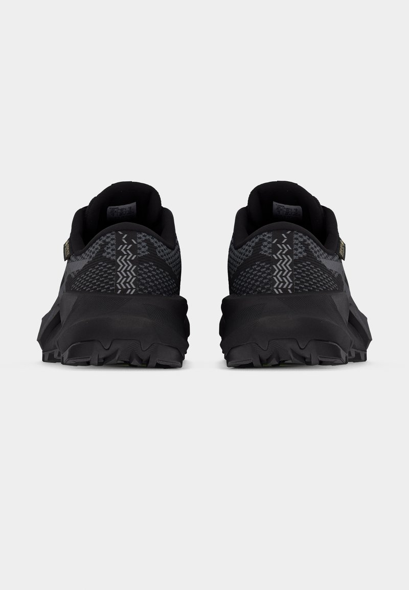 Paire de chaussures de sport noires et grises vues de dos, avec des tiges en maille à motifs et des semelles épaisses et robustes.