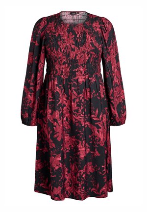 Sort langærmet kjole med rødt blomsterprint, smocket bærestykke og samlet talje, der har en rund udskæring.