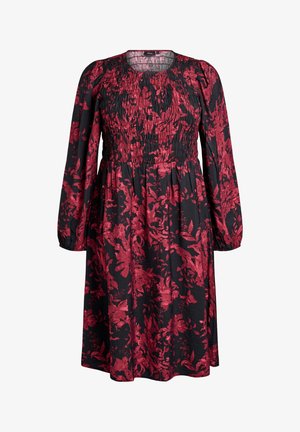 Sort langærmet kjole med rødt blomsterprint, smocket bærestykke og samlet talje, der har en rund udskæring.