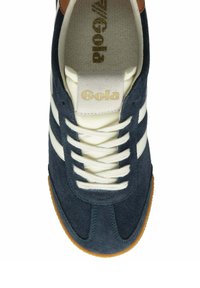 Sneaker in suede blu navy con strisce e lacci color crema. Accentatura in pelle marrone sul tallone. Logo bianco sulla linguetta. Suola in gomma con grip testurizzato.