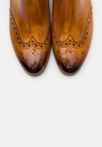 Zapatos de vestir de piel marrón con un diseño brogue, que presentan perforaciones decorativas y un acabado suave que se transiciona a una puntera más oscura.