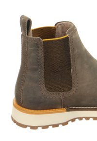 Braune Leder Chelsea-Stiefel mit elastischen Seitenpaneelen, einer strukturierten Oberfläche, gelber Innenausstattung und einer robusten weißen Gummisohle.