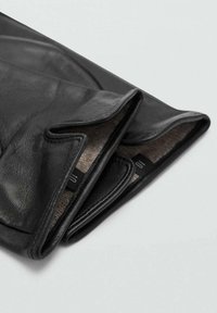 Guantes de cuero negro con un forro interno suave, que presentan una textura lisa y un sutil detalle de costura en las aperturas de los puños.