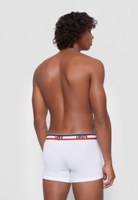White cotton boxer shorts with a black, red, and blue elastic waistband featuring "Levi's" branding. The model is shown from the back.