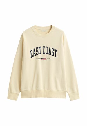 Roomkleurige sweatshirt met lange mouwen met de tekst "EAST COAST" en een klein Amerikaans vlagembleem op de voorkant.