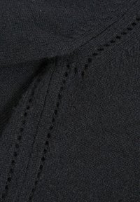 Tessuto di maglia nera con una texture liscia, caratterizzato da un motivo di piccoli fori lungo una cucitura, creando un delicato contrasto.
