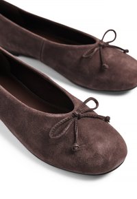 Ruskean mokkanahka ballet-tyyliset kengät, joissa on pyöreä nenä ja koristeellinen sulkavyö etuosassa. Pehmeä koostumus ja minimalistinen muotoilu.