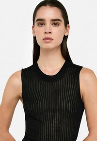 Top senza maniche di colore nero realizzato in tessuto rib ribattezzato, leggermente testurizzato, con scollatura rotonda e una sottile lucentezza. Design aderente che enfatizza la forma del corpo.