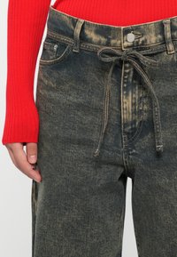 Denim bukser i en falmet sort vask med en løs pasform, der har en bundet snøre detalje i taljen og et klassisk fem-lomme design.