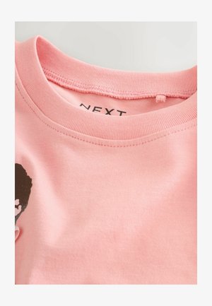 T-shirt in cotone rosa chiaro con scollo rotondo, maniche corte e un design grafico nero sulla parte frontale. Etichetta del marchio visibile all'interno del colletto.