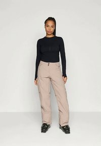 Μαύρη μπλούζα με μακριά μανίκια και ραφή μπροστά; μπεζ παντελόνι φάρδους με δύο μπροστινές τσέπες; μαύρα σκι μποτάκια. Απλός, λειτουργικός σχεδιασμός.