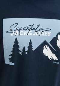 Navy-blaues Baumwoll-T-Shirt mit einem hellblauen Grafikdesign, das stilisierte Bäume und Berge zeigt, sowie dem Text "Essentials JACK&JONES."