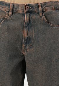 Donkerdenim jeans met contrasterende oranje stiksels, voorzien van een knoopsluiting, vijf zakken en een gestructureerde afwerking.