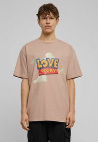 Light pink t-shirt in cotton, featuring a large "LOVE STORY" graphic in blue and red, with cloud accents printed in white. Short sleeves.