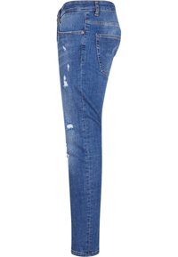 Chudé modré džínsy z denimu s poškodenými miestami, dizajn so piatimi vreckami a stredným pásom. Majú svetlé vyblednutie a jemné stehenné akcenty.