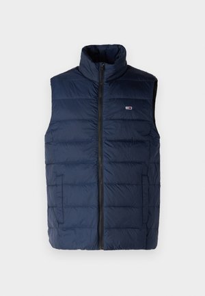 Tumedat sinise värvi puhvrivest kõrge kraega, ees lukuga ja horisontaalsete õmblustega; omaduseks on väikene logo rinnal ja küljetaskud.